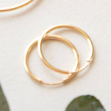 Two gold hoop earrings on a light background