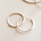 Silver hoop earrings on a light beige surface