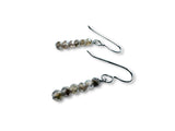 Pair of earrings with beaded design on a white background. Metallic coated moonstone earrings.