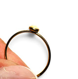 A close-up of a gold ring being held between fingers against a plain white background.