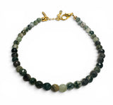 Necklace with green and black beaded chain on a white background