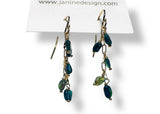 Pair of green beaded earrings on a white background with Janine Design branding.