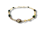 Gold bracelet with green and purple beads on a white background