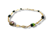 Gold bracelet with green and purple gemstone beads on a white background