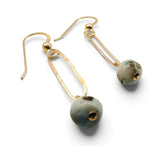 A pair of gold drop earrings with elongated open-frame hooks and round, textured gray-green beads featuring small gold accents, shown on a plain white background.