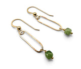 A pair of gold dangle earrings with elongated open oval hooks and faceted green gemstone drops, shown on a clean white background.