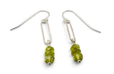 A pair of silver drop earrings with elongated rectangular silver wire charms and three faceted green gemstone beads hanging from each earring, shown on a plain white background.