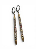Pair of long, thin earrings with decorative elements on a white background