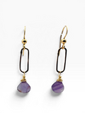 A pair of gold and black drop earrings with teardrop-shaped purple stone pendants, shown on a clean white background.