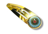 Gold hair clip with a colorful circular design on a white background