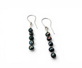A pair of silver-tone dangle earrings with four dark, iridescent baroque pearls hanging from silver French hooks, shown on a plain white background.