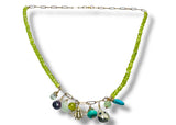 Necklace with green beads and colorful charms on a white background