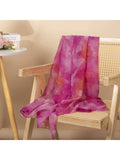 Pink and orange scarf draped over a wooden chair against a beige wall.