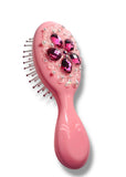 Pink hairbrush with decorative elements on a white background