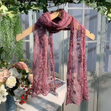 Pink lace scarf on a mannequin with flowers and greenery in the background