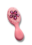 Pink hairbrush with decorative gemstones on a white background