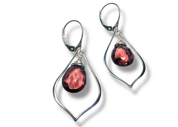 Silver earrings with red gemstones on a white background
