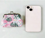 Floral-patterned coin purse next to a pink phone on a light gray background
