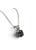 A silver-toned necklace with a delicate chain and a pendant featuring a dark, iridescent oval gemstone in a prong setting, shown on a plain white background.