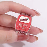 Red 'neuro spicy' enamel pin held between fingers on a white background
