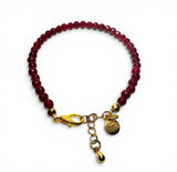 Bracelet with red beads and gold clasp on a white background