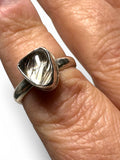 Hand wearing a silver ring with a large Rutilated Quartz  on a white background