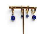 Set of gold hoop earrings with blue evil eye charms on a white background