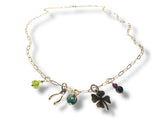 Gold necklace with charms including a four-leaf clover, green bead, and other small pendants on a white background.