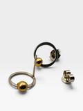 Abstract geometric earrings with circular rings and polished gold-toned spheres, shown on a clean light gray background with one earring displayed front-facing and the other at an angle with its post visible.