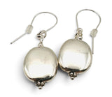A pair of silver drop earrings with smooth, polished oval-shaped beads and small beaded accents at the bottom, suspended from classic fishhook wires on a white background.