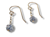 Gold earrings with clear gemstones on a white background