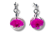 Pair of earrings with pink floral elements in clear circular settings on a white background