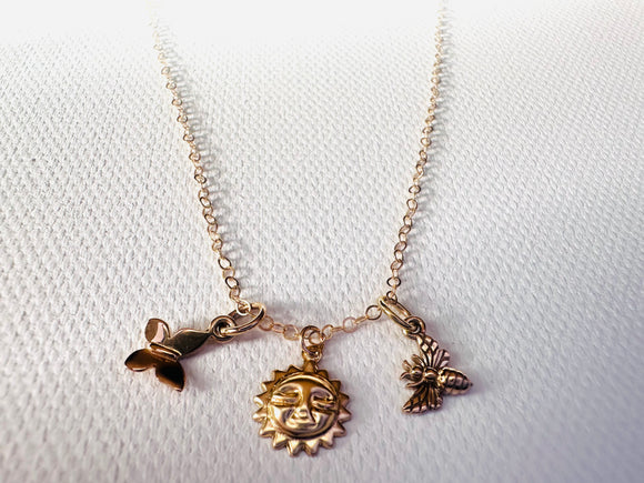 Gold necklace with three charms on a white background