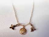 Gold necklace with three charms on a white background