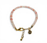 Bracelet with pink beads and gold clasp on a white background