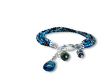 Multistrand bracelet with blue and black beads and silver charms on a white background. Topaz and Sapphire Triple Bracelet