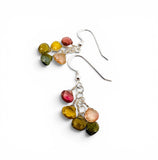 A pair of handmade dangle earrings featuring faceted, irregular gemstones in yellow, green, pink, and peach, suspended from silver fishhook wires on a plain white background.