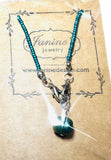 Turquoise beaded necklace with a pendant on a Famine Jewelry card.