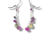 Silver earrings with purple and green gemstones on a white background