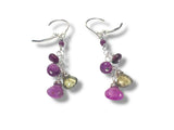 Pair of earrings with purple and yellow gemstones on a white background