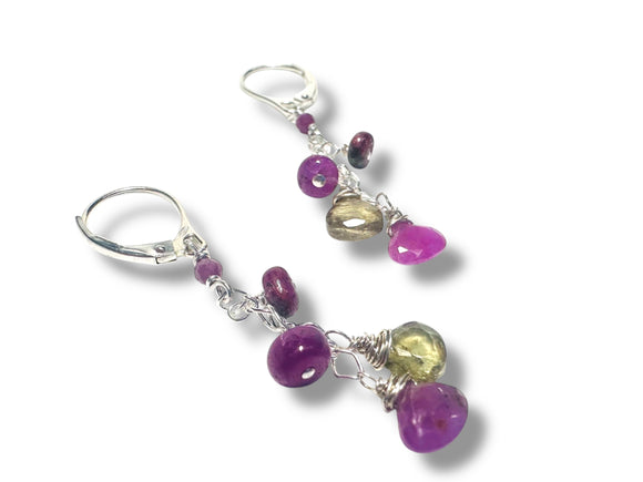 Pair of earrings with purple and green beads on a white background