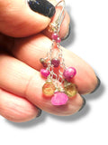 Close-up of a hand holding a pair of multicolored bead earrings.