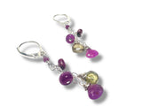 Pair of earrings with purple and green beads on a white background