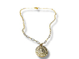 Gold necklace with a round pendant on a white background