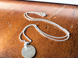 Silver necklace with a pendant on a wooden surface