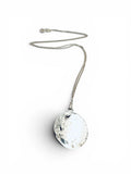 A silver-toned necklace featuring a hammered, textured oval pendant on a delicate chain, photographed against a clean white background.