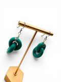 Green chain-link earrings on a gold stand against a white background