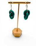 Green earrings on a gold stand against a white background