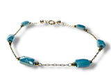 Bracelet with blue beads and gold chain on a white background