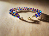 Woven Crystal Bracelet/7.5” bracelet pink/blue crystals woven with tiny gold seed beads. shown on wood background